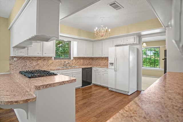 30814 Quinn Rd, Tomball, TX 77375 - kitchen with white fridge with ice dispenser, a chandelier, light countertops, light wood-style floors, and decorative backsplash