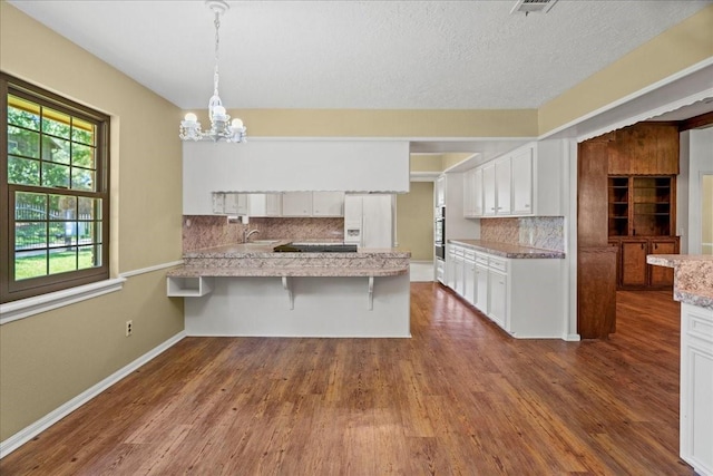 30814 Quinn Rd, Tomball, TX 77375 - kitchen featuring a peninsula, backsplash, a sink, dark wood-style flooring, and white cabinetry