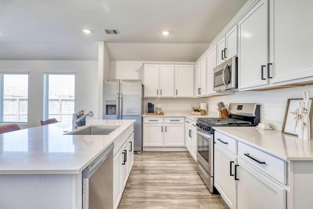 1386 Antigua Dr, Conroe, TX 77301 - kitchen with appliances with stainless steel finishes, a sink, white cabinets, a center island with sink, and recessed lighting