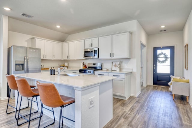 1386 Antigua Dr, Conroe, TX 77301 - kitchen featuring stainless steel appliances, a sink, light wood-style floors, an island with sink, and a breakfast bar area