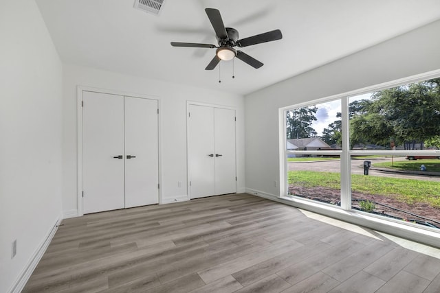 9602 Ballin David Dr, Spring, TX 77379 - unfurnished bedroom with wood finished floors, two closets, baseboards, and ceiling fan