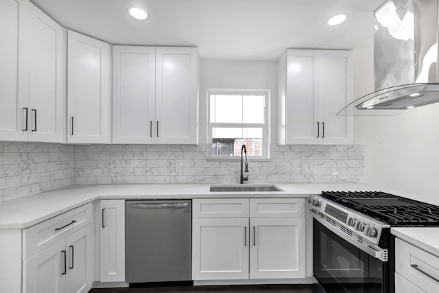 9602 Ballin David Dr, Spring, TX 77379 - kitchen with stainless steel appliances, wall chimney exhaust hood, a sink, white cabinetry, and tasteful backsplash