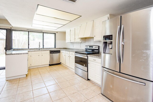 16806 Grampin Dr, Houston, TX 77084 - kitchen featuring stainless steel appliances, custom exhaust hood, light tile patterned flooring, and a sink