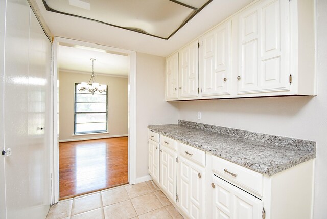16806 Grampin Dr, Houston, TX 77084 - kitchen with white cabinetry, light countertops, light tile patterned floors, a chandelier, and baseboards