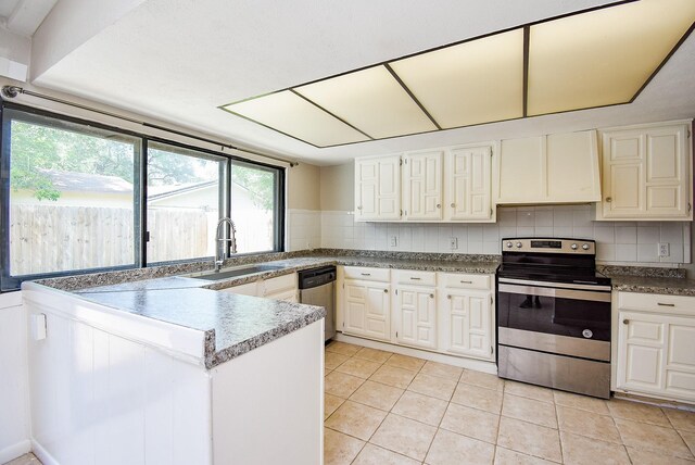 16806 Grampin Dr, Houston, TX 77084 - kitchen featuring appliances with stainless steel finishes, a sink, a peninsula, light tile patterned flooring, and decorative backsplash