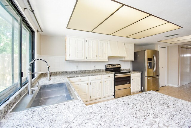 16806 Grampin Dr, Houston, TX 77084 - kitchen with stainless steel appliances, premium range hood, a sink, white cabinets, and light tile patterned floors