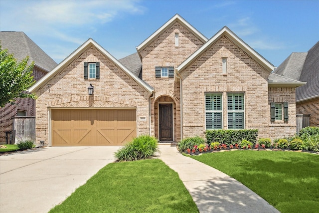 5131 Anthony Springs Ln, Sugar Land, TX 77479 - french country home with concrete driveway, brick siding, a front yard, and a garage