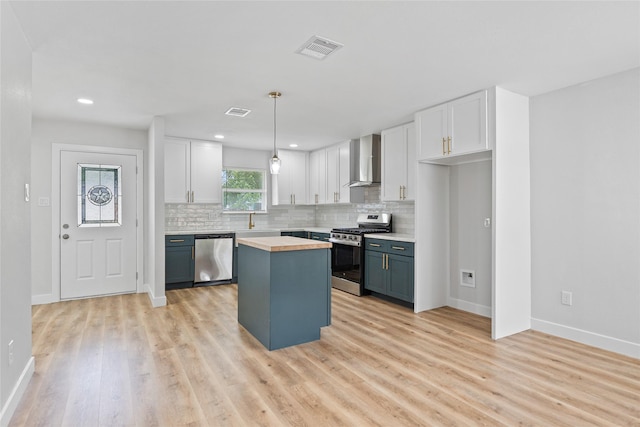 5115 Clay St, Houston, TX 77023 - kitchen with stainless steel appliances, wall chimney range hood, wooden counters, white cabinets, and recessed lighting