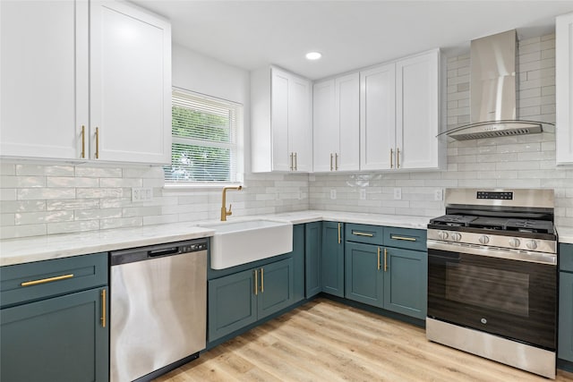 5115 Clay St, Houston, TX 77023 - kitchen with stainless steel appliances, wall chimney range hood, a sink, white cabinetry, and recessed lighting