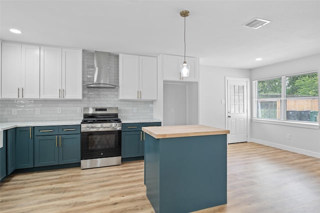 5115 Clay St, Houston, TX 77023 - kitchen with gas stove, wall chimney exhaust hood, white cabinetry, light wood-style flooring, and recessed lighting