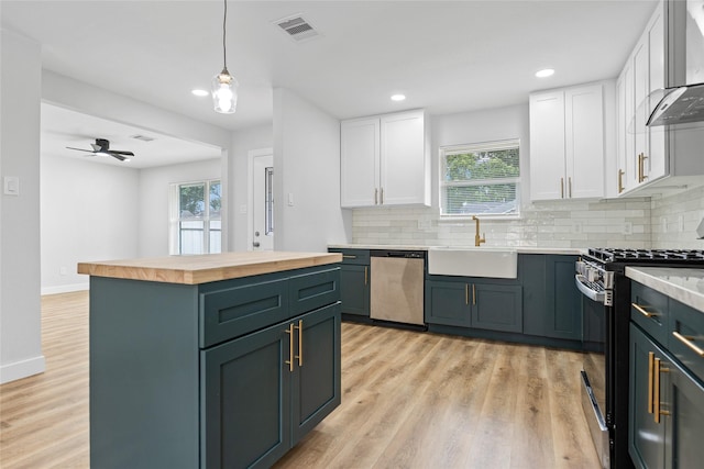 5115 Clay St, Houston, TX 77023 - kitchen with stainless steel appliances, wood counters, a sink, white cabinets, and recessed lighting