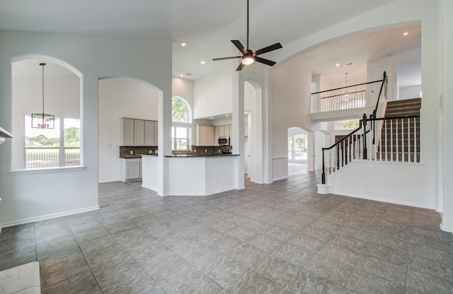 24206 Moon Ridge Ct, Katy, TX 77494 - unfurnished living room with a towering ceiling, a ceiling fan, recessed lighting, stairs, and arched walkways
