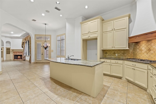 16610 Champagne Falls Ct, Spring, TX 77379 - kitchen featuring cream cabinets, backsplash, a fireplace, recessed lighting, and a sink