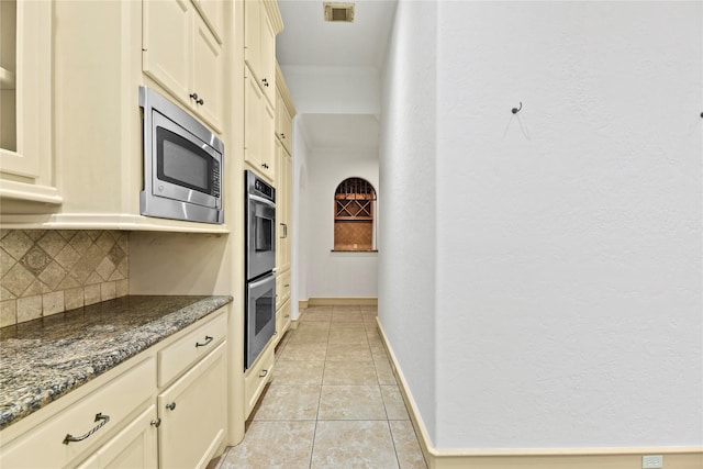 16610 Champagne Falls Ct, Spring, TX 77379 - kitchen with appliances with stainless steel finishes, tasteful backsplash, dark stone countertops, light tile patterned floors, and baseboards
