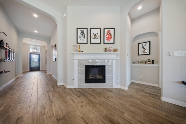 24103 Corinaldo Ct, Katy, TX 77493 - unfurnished living room featuring wood finished floors, arched walkways, recessed lighting, baseboards, and a tiled fireplace