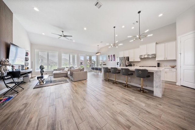 24103 Corinaldo Ct, Katy, TX 77493 - living room with high vaulted ceiling, recessed lighting, light wood finished floors, a ceiling fan, and a chandelier