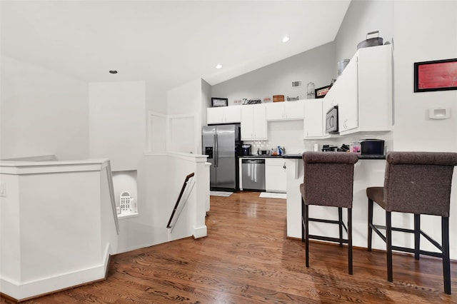 914 W 25th St Unit 2, Houston, TX 77008 - kitchen with stainless steel appliances, a peninsula, white cabinets, a kitchen breakfast bar, and dark wood-style floors