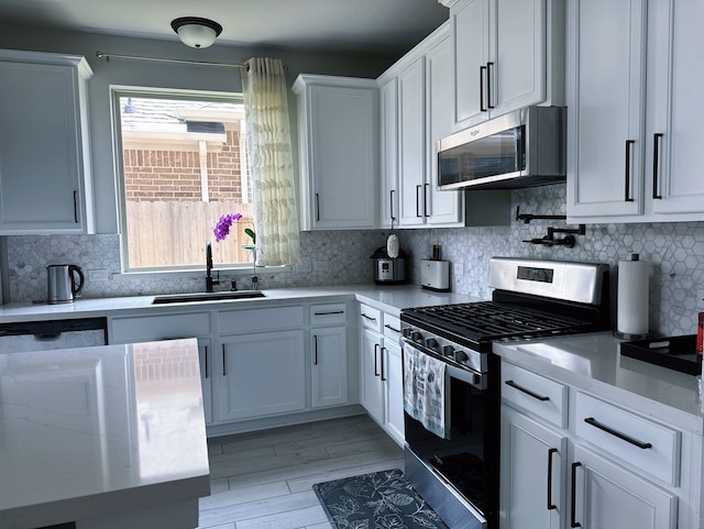 31414 Golden Cliffs Ln, Fulshear, TX 77441 - kitchen featuring stainless steel appliances, a sink, tasteful backsplash, white cabinets, and light wood-style floors