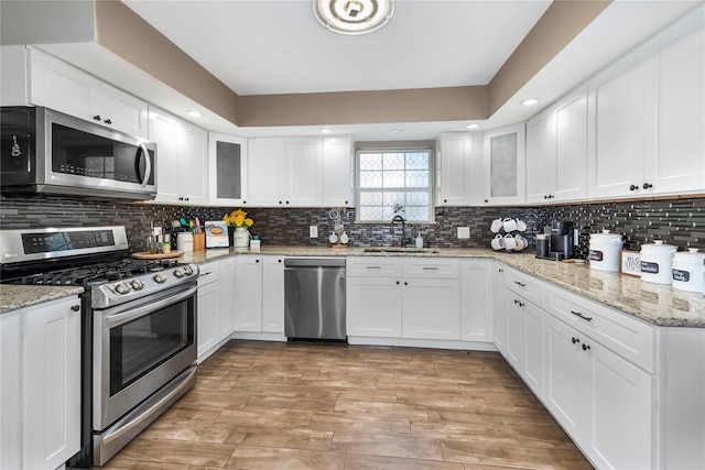 676 Ravensworth Dr, Conroe, TX 77302 - kitchen featuring appliances with stainless steel finishes, a sink, white cabinets, and light wood-type flooring