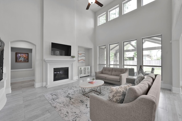 503 Woodsy Pine Ct, Conroe, TX 77304 - living room with a towering ceiling, a glass covered fireplace, a ceiling fan, and baseboards