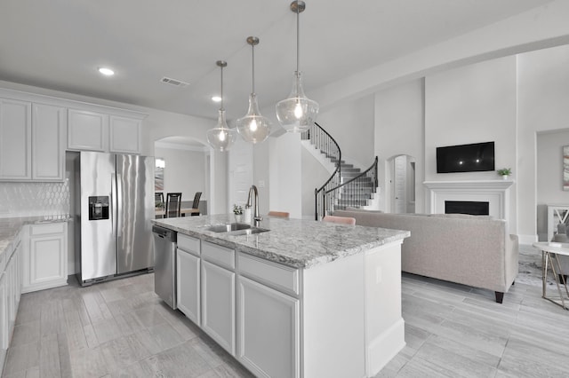 503 Woodsy Pine Ct, Conroe, TX 77304 - kitchen featuring appliances with stainless steel finishes, arched walkways, a sink, recessed lighting, and light stone countertops
