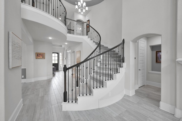 503 Woodsy Pine Ct, Conroe, TX 77304 - stairs with a towering ceiling, arched walkways, baseboards, a chandelier, and wood finished floors