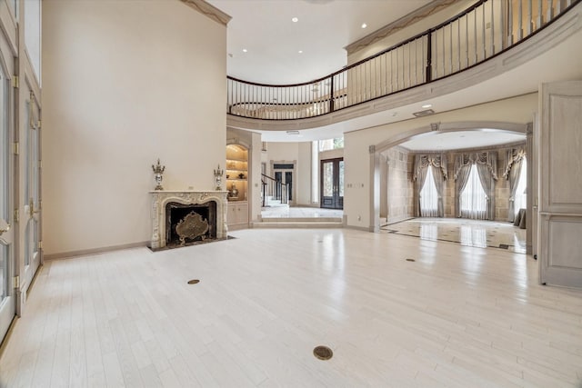 903 Old Lake Rd, Houston, TX 77057 - unfurnished living room with a towering ceiling, wood finished floors, arched walkways, baseboards, and a premium fireplace