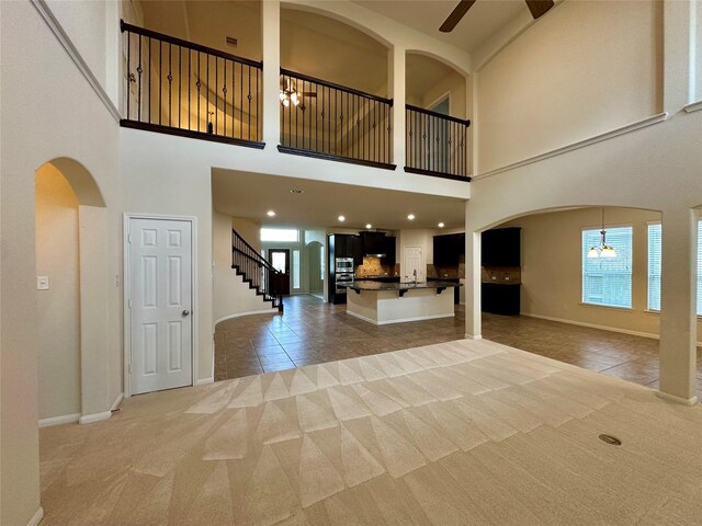 9314 Wheatfield Ln, Rosenberg, TX 77469 - foyer entrance with ceiling fan, light colored carpet, light tile patterned floors, arched walkways, and a towering ceiling