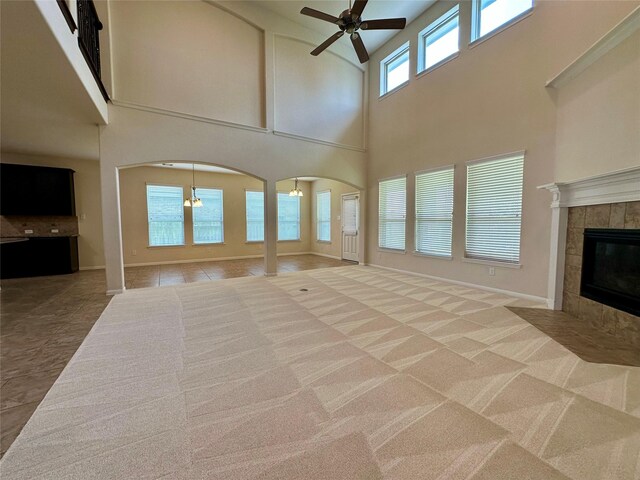 9314 Wheatfield Ln, Rosenberg, TX 77469 - unfurnished living room featuring a high ceiling, a ceiling fan, arched walkways, a tile fireplace, and baseboards