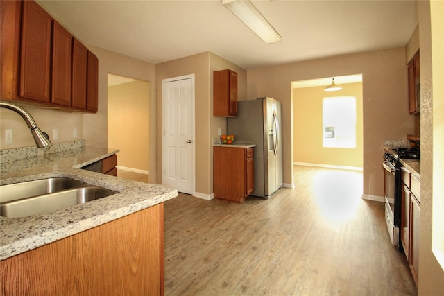 16726 Warbler Dr, Conroe, TX 77385 - kitchen with range with gas stovetop, a sink, stainless steel fridge with ice dispenser, and brown cabinets
