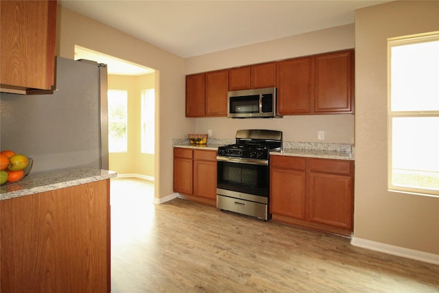 16726 Warbler Dr, Conroe, TX 77385 - kitchen featuring stainless steel appliances, brown cabinets, light wood finished floors, and plenty of natural light