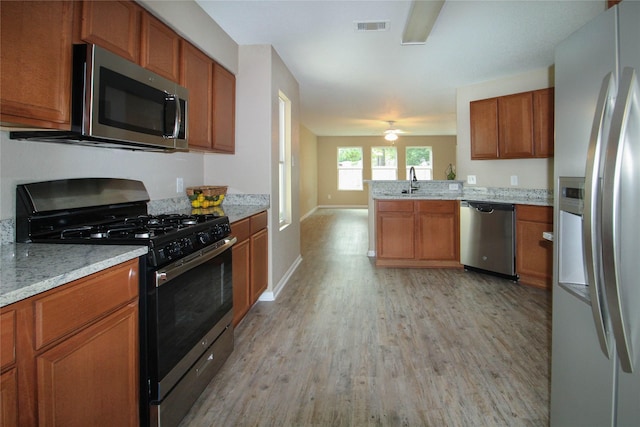 16726 Warbler Dr, Conroe, TX 77385 - kitchen featuring stainless steel appliances, light wood-type flooring, brown cabinets, a peninsula, and ceiling fan