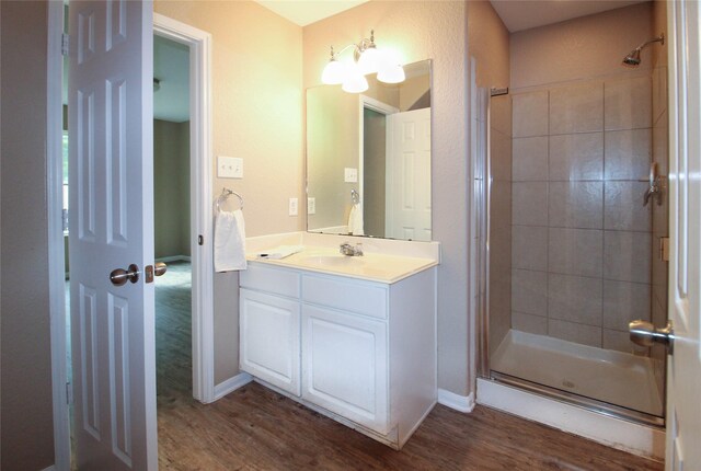 16726 Warbler Dr, Conroe, TX 77385 - full bathroom featuring wood finished floors, a stall shower, vanity, and baseboards