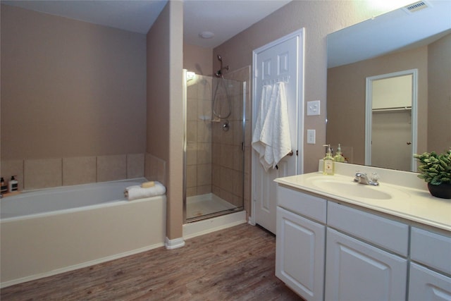 16726 Warbler Dr, Conroe, TX 77385 - bathroom with a shower stall, wood finished floors, a bath, vanity, and a walk in closet
