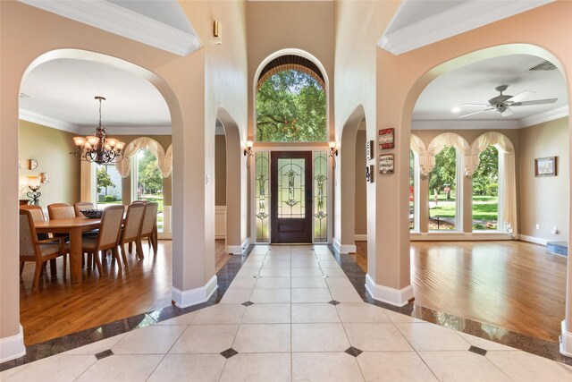 5706 Amber Queen Ct, Houston, TX 77041 - entrance foyer featuring light tile patterned floors, inlaid floor details, a chandelier, arched walkways, and crown molding