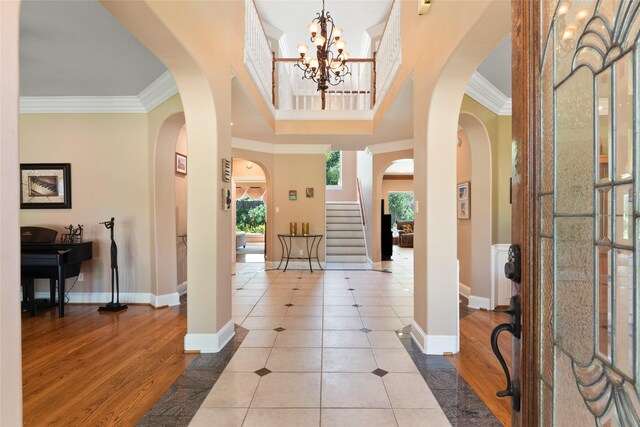 5706 Amber Queen Ct, Houston, TX 77041 - tiled entrance foyer featuring crown molding, arched walkways, baseboards, a chandelier, and stairway