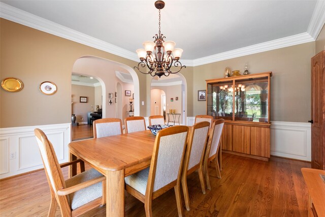 5706 Amber Queen Ct, Houston, TX 77041 - dining space with a wainscoted wall, arched walkways, crown molding, a chandelier, and light wood-type flooring