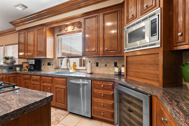 5706 Amber Queen Ct, Houston, TX 77041 - kitchen with wine cooler, appliances with stainless steel finishes, a sink, decorative backsplash, and brown cabinets