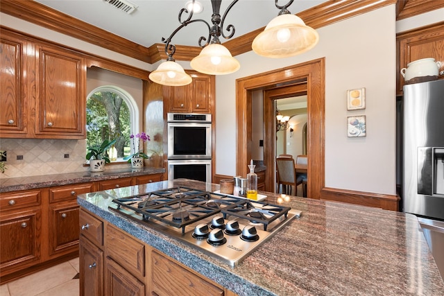 5706 Amber Queen Ct, Houston, TX 77041 - kitchen featuring appliances with stainless steel finishes, brown cabinets, decorative backsplash, decorative light fixtures, and crown molding
