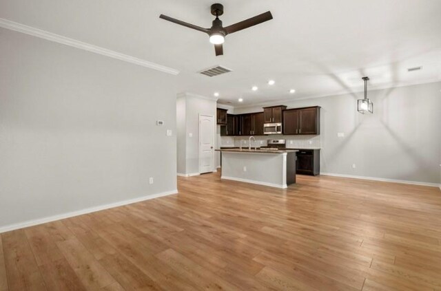 910 S Chamfer Way, Crosby, TX 77532 - unfurnished living room with ceiling fan, a sink, baseboards, crown molding, and light wood-style floors