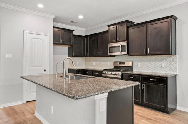 910 S Chamfer Way, Crosby, TX 77532 - kitchen with stainless steel appliances, a sink, dark stone counters, light wood-style floors, and ornamental molding