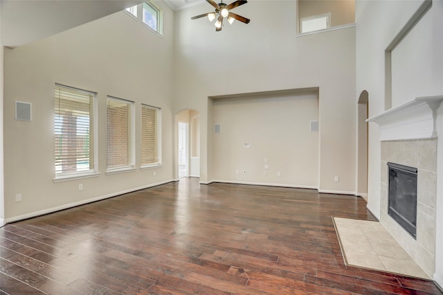 5402 Bending Branch Dr, Missouri City, TX 77459 - unfurnished living room featuring a ceiling fan, a high ceiling, wood-type flooring, a fireplace, and arched walkways