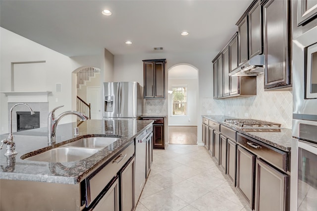5402 Bending Branch Dr, Missouri City, TX 77459 - kitchen with arched walkways, stainless steel appliances, a sink, dark stone countertops, and recessed lighting