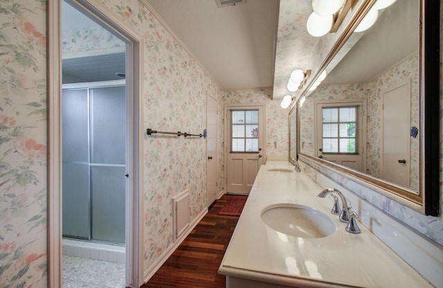 6119 Bankside Dr, Houston, TX 77096 - full bathroom with wallpapered walls, wood finished floors, double vanity, a stall shower, and baseboards