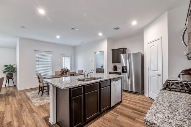 15007 Ashton Meadows Dr, New Caney, TX 77357 - kitchen with stainless steel appliances, a sink, an island with sink, light wood-style floors, and dark brown cabinetry