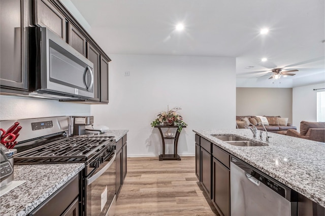 15007 Ashton Meadows Dr, New Caney, TX 77357 - kitchen with appliances with stainless steel finishes, a sink, recessed lighting, light stone countertops, and dark brown cabinets