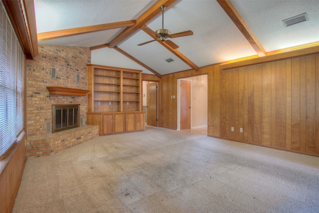 333 Hardy St, Huntsville, TX 77340 - unfurnished living room with a ceiling fan, wooden walls, carpet flooring, a fireplace, and a textured ceiling