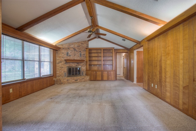 333 Hardy St, Huntsville, TX 77340 - unfurnished living room with wood walls, ceiling fan, carpet flooring, a brick fireplace, and a textured ceiling
