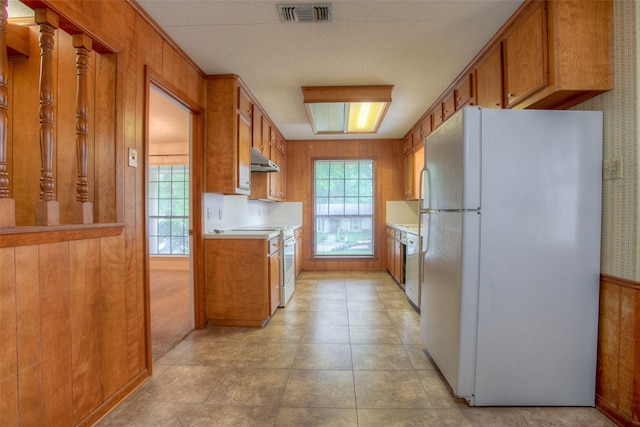 333 Hardy St, Huntsville, TX 77340 - kitchen featuring white appliances, brown cabinetry, under cabinet range hood, light countertops, and wallpapered walls