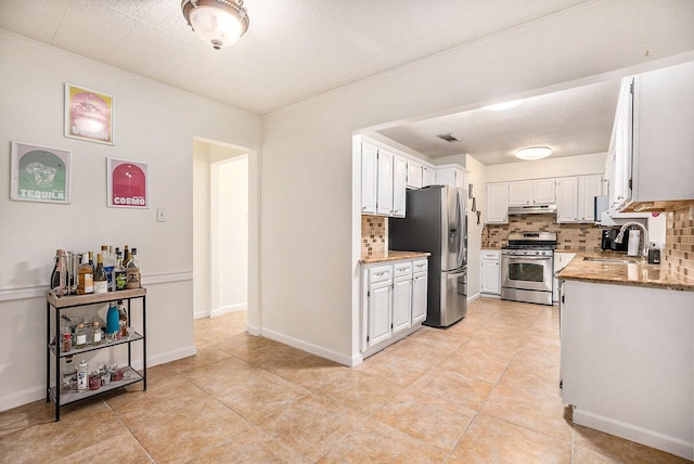 116 Whiting St, Galveston, TX 77550 - kitchen featuring appliances with stainless steel finishes, a sink, under cabinet range hood, backsplash, and white cabinets